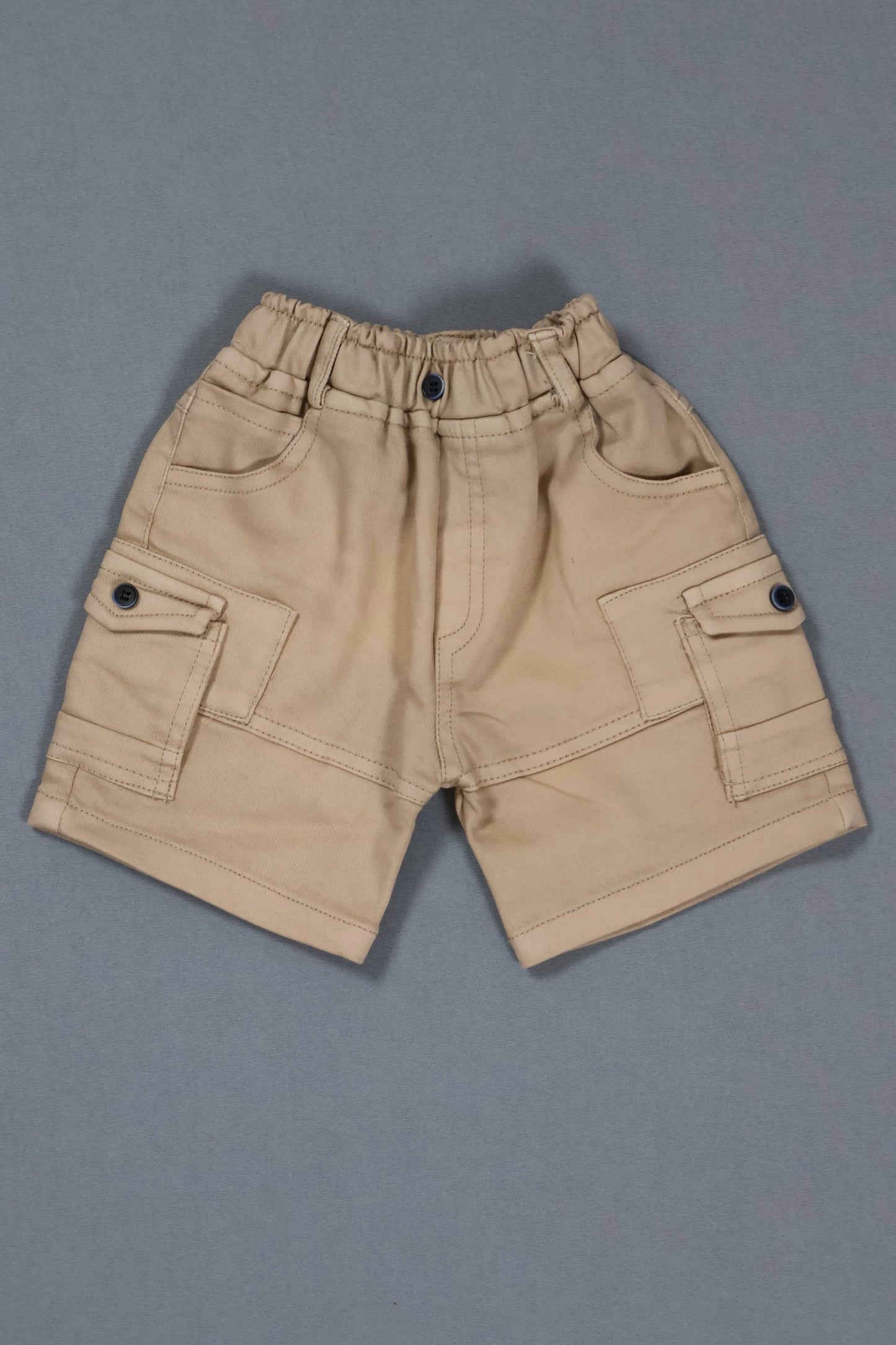 Beige shorts with button details on a gray background
