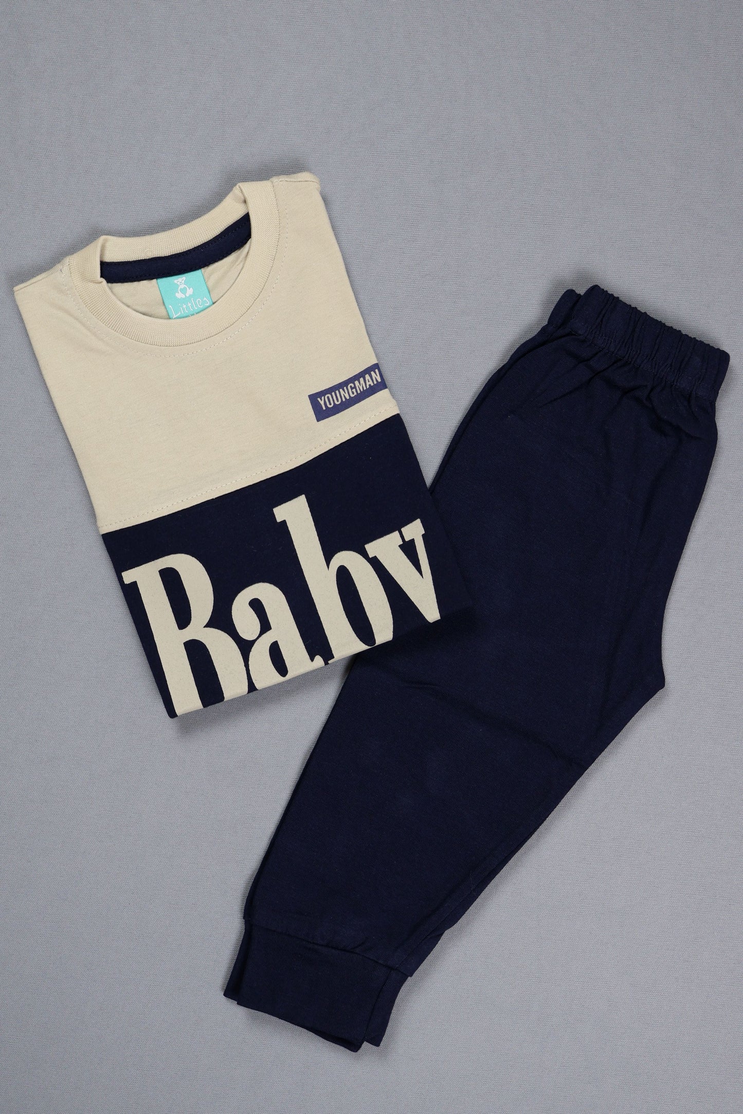 Navy baby pants and a cream-colored t-shirt with text on a gray background