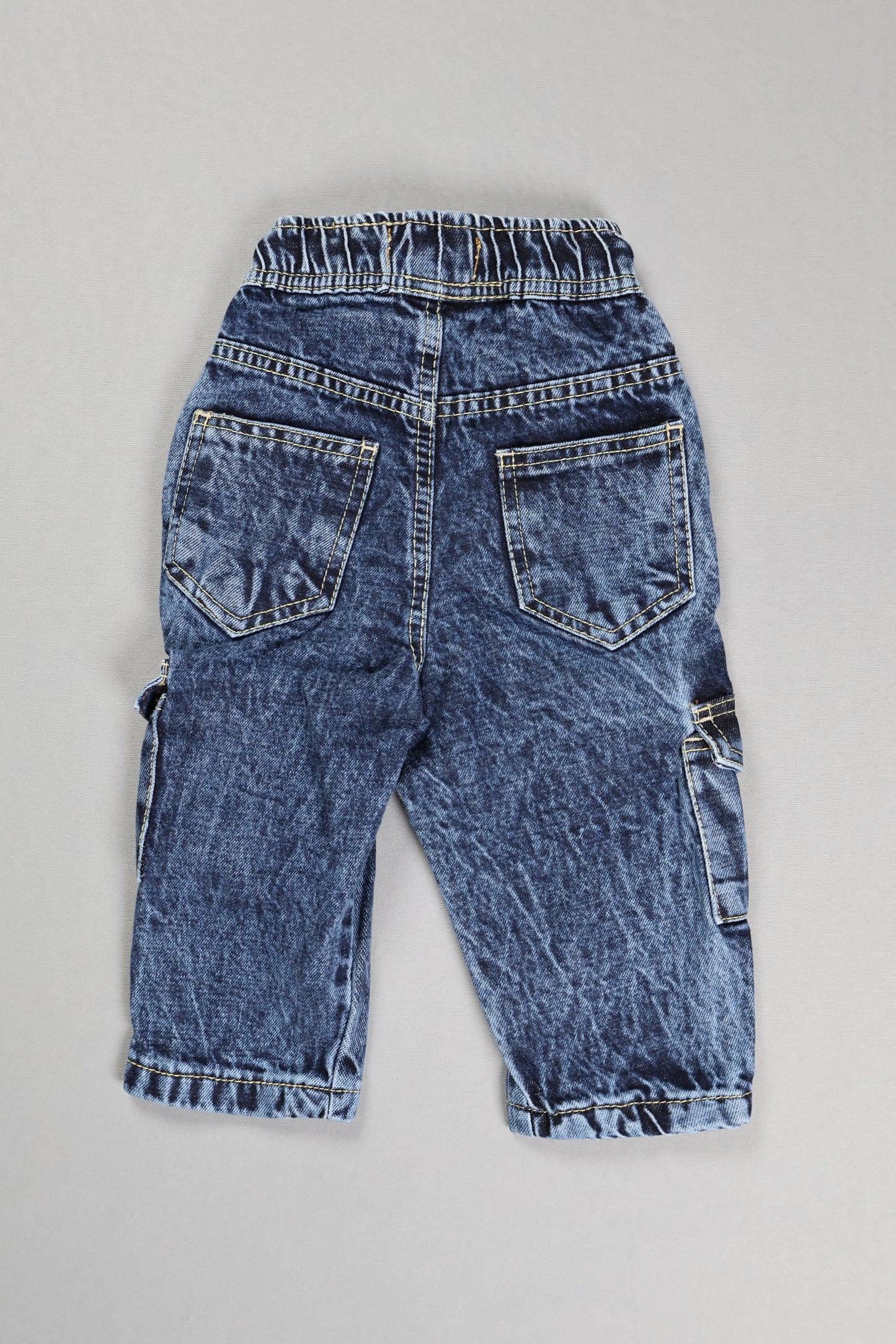 Pair of blue jeans laid flat on a gray surface