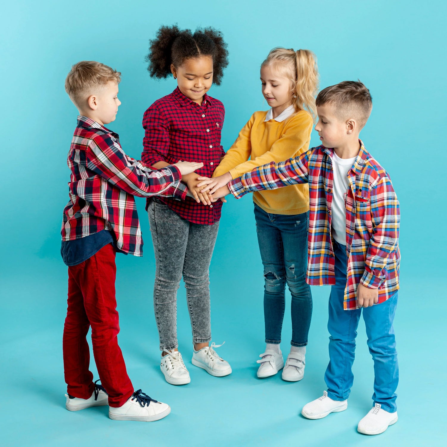 Group of kids in colorful cotton clothes joining hands on blue background