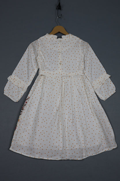 White cotton kids dress with brown polka dots, long sleeves, and ruffle details