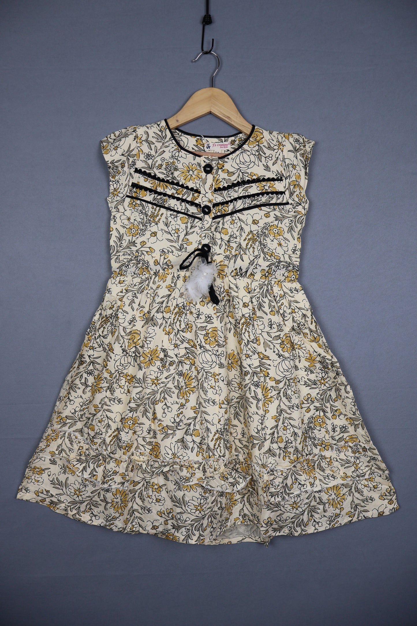 Girls' sleeveless cotton floral dress in yellow and grey with black lace trim, displayed on hanger.