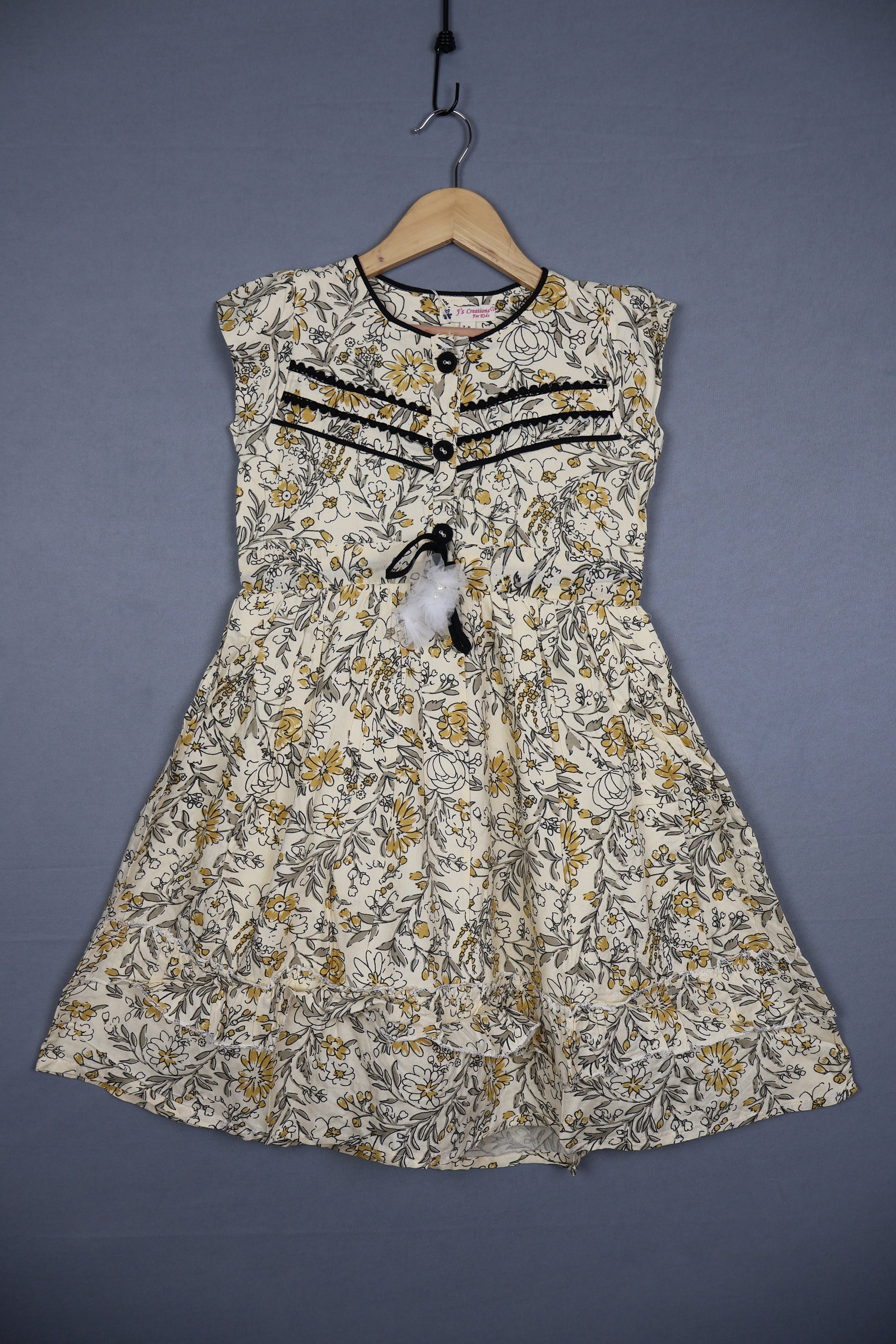 Girls' sleeveless cotton floral dress in yellow and grey with black lace trim, displayed on hanger.