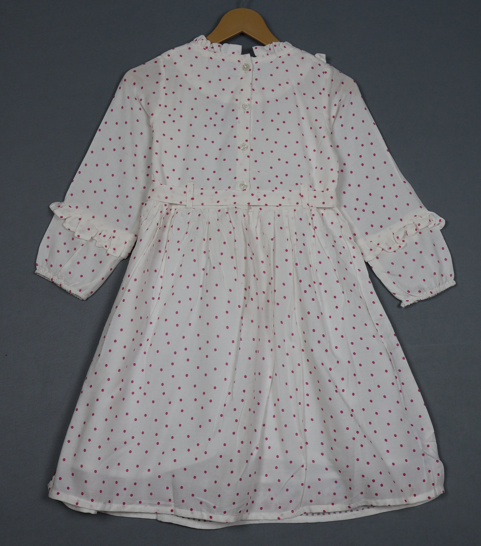White dress with red patterns on a hanger against a dark background