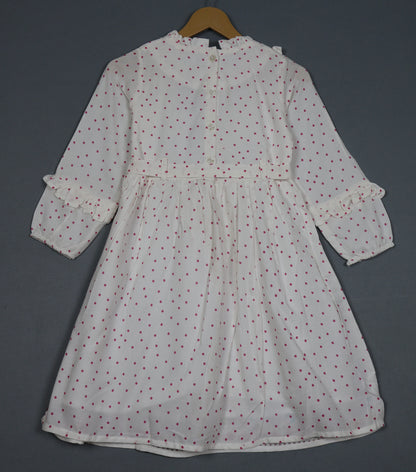 White dress with red patterns on a hanger against a dark background