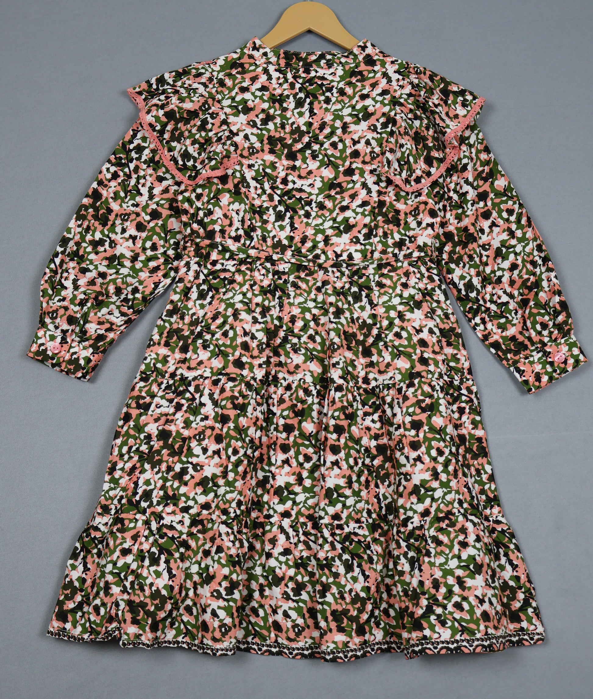 Floral patterned dress on a hanger against a gray background