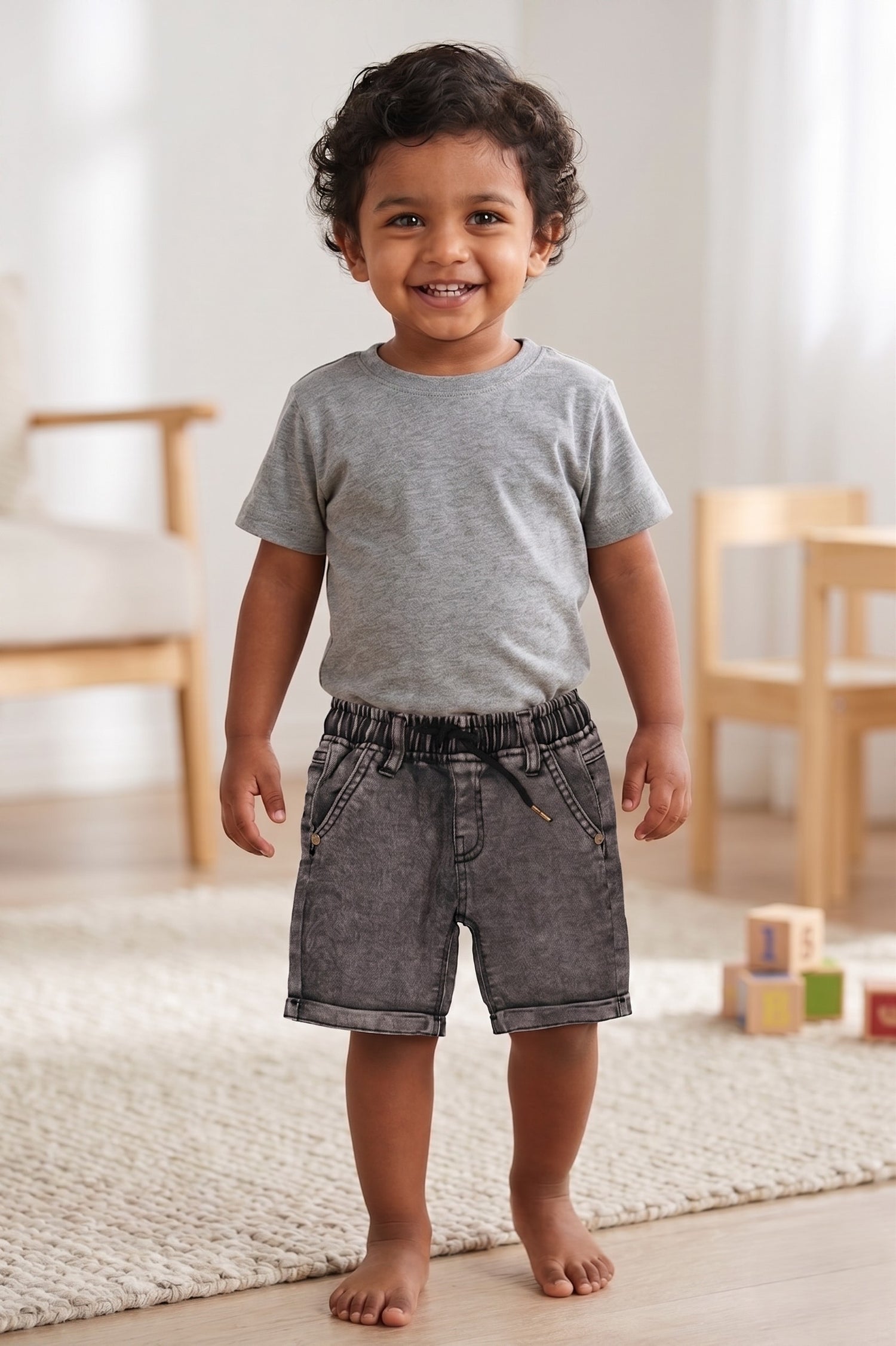 A kid wearing FYST brand lightweight charcoal grey acid-wash denim shorts featuring a comfortable elasticated waistband with a black drawstring and folded hem detailing.
