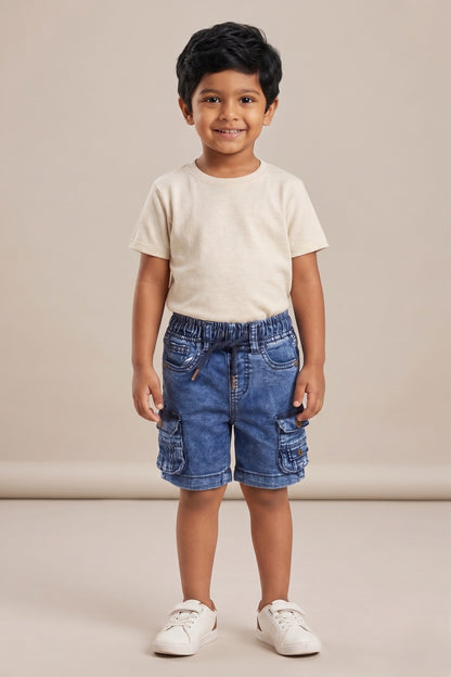 A kid wearing FYST brand lightweight acid-wash denim cargo shorts featuring an elastic drawstring waistband and functional side flap pockets with button details.