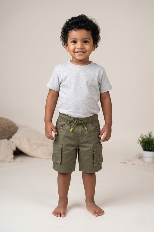 A kid wearing FYST brand lightweight olive green cargo shorts featuring a comfortable elastic drawstring waistband with lime green tips and multiple functional side flap pockets.