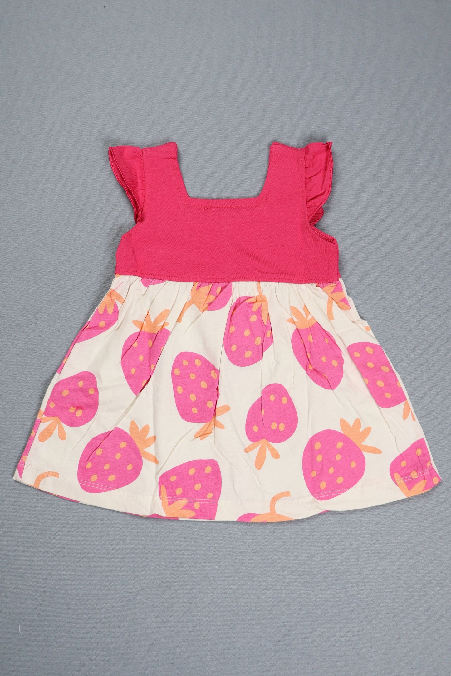 Children's dress with pink top and strawberry patterned skirt on a gray background