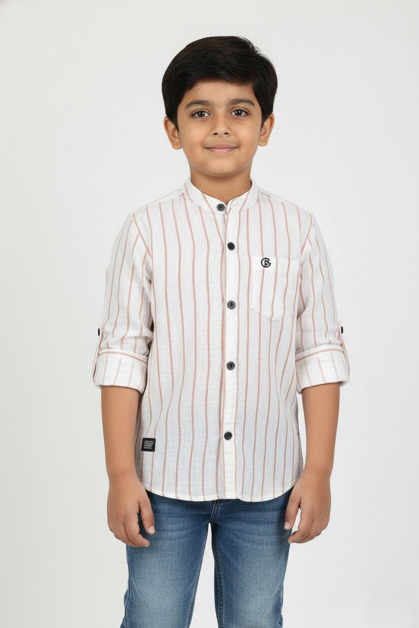 A young boy models a Fyst brand long-sleeve, linen-texture button-down shirt with a mandarin collar. The shirt is off-white with thin vertical brown pinstripes and features contrasting black buttons and rolled-up sleeves, paired with blue jeans.