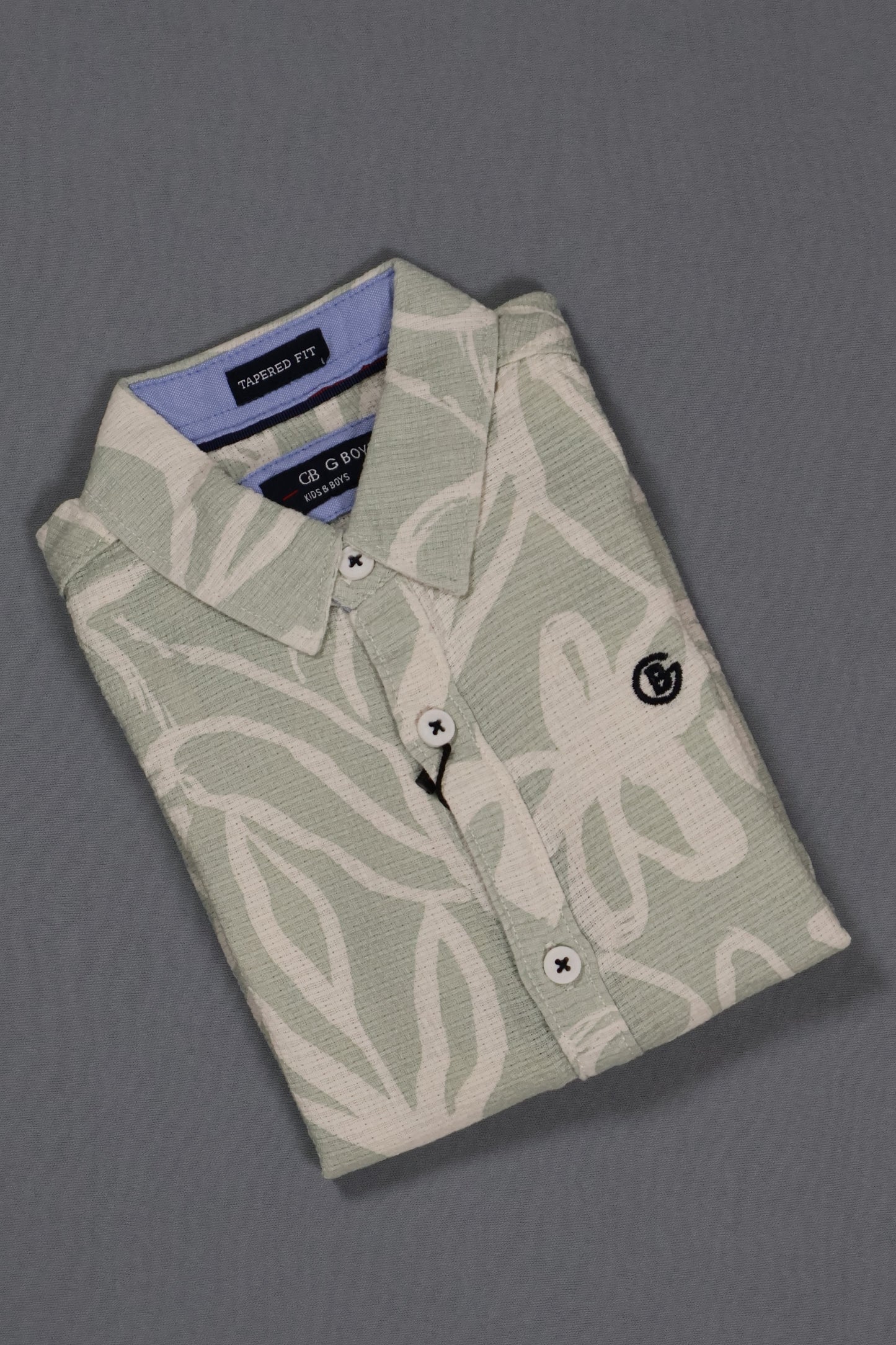 Folded light green shirt with white patterns on a gray background