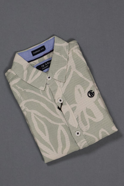 Folded light green shirt with white patterns on a gray background