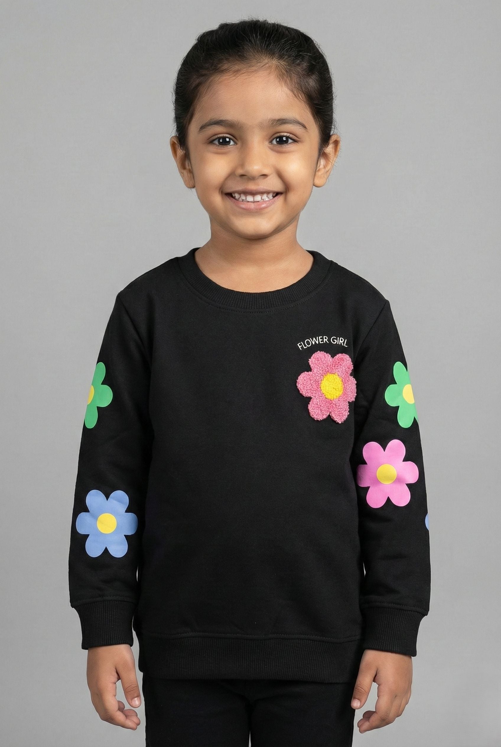 A black long-sleeved sweatshirt featuring the text 'FLOWER GIRL' curved above a small, textured pink flower on the left chest. The sleeves are decorated with large, colorful flower prints in blue, green, and pin
