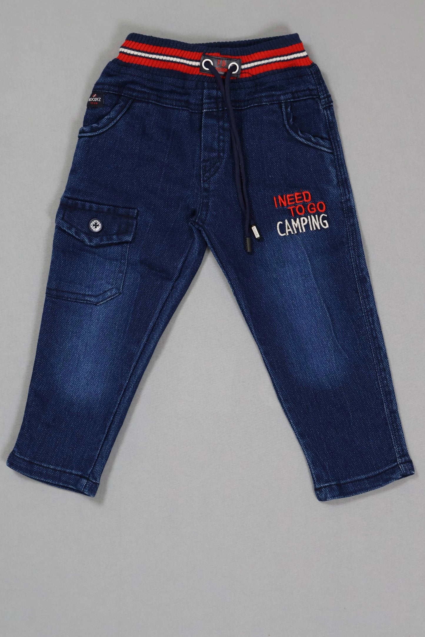 Blue jeans with a red and white striped waistband on a gray background