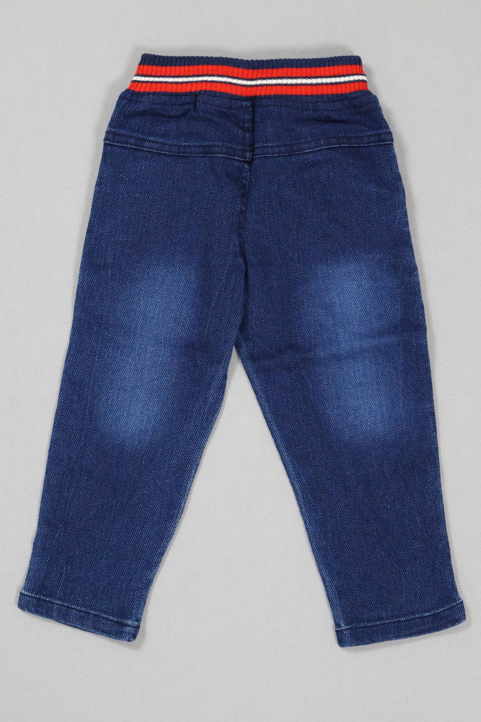 Blue jeans with a striped waistband on a gray background