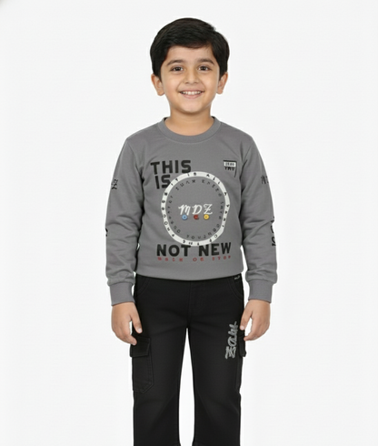 Child wearing a gray long-sleeve shirt with text and black pants on a white background
