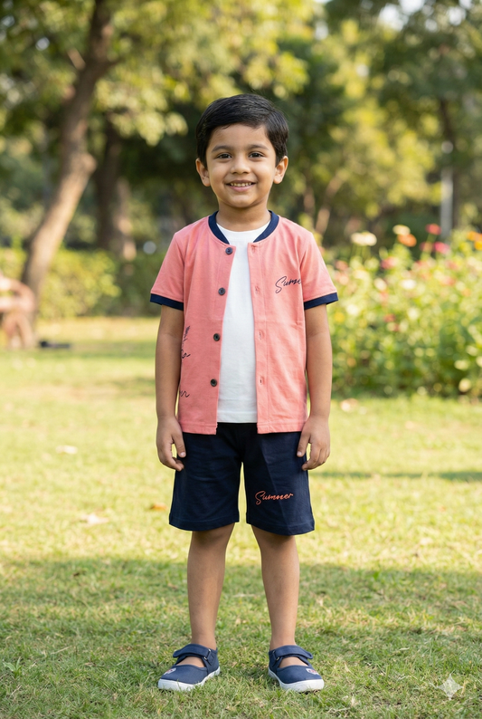 A young boy modeling a coral pink three-piece summer set. The outfit includes an unbuttoned coral shirt with "Summer" script on the chest, a white inner t-shirt, and matching coral shorts. He is standing outdoors on a sunny lawn wearing blue slip-on shoes.