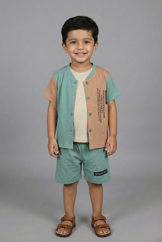 A young boy modeling a stylish three-piece summer set. The outfit features a sage green and sand brown color-block button-down shirt worn over a cream inner t-shirt, paired with matching sage green shorts. He is standing against a neutral grey background wearing brown sandals.