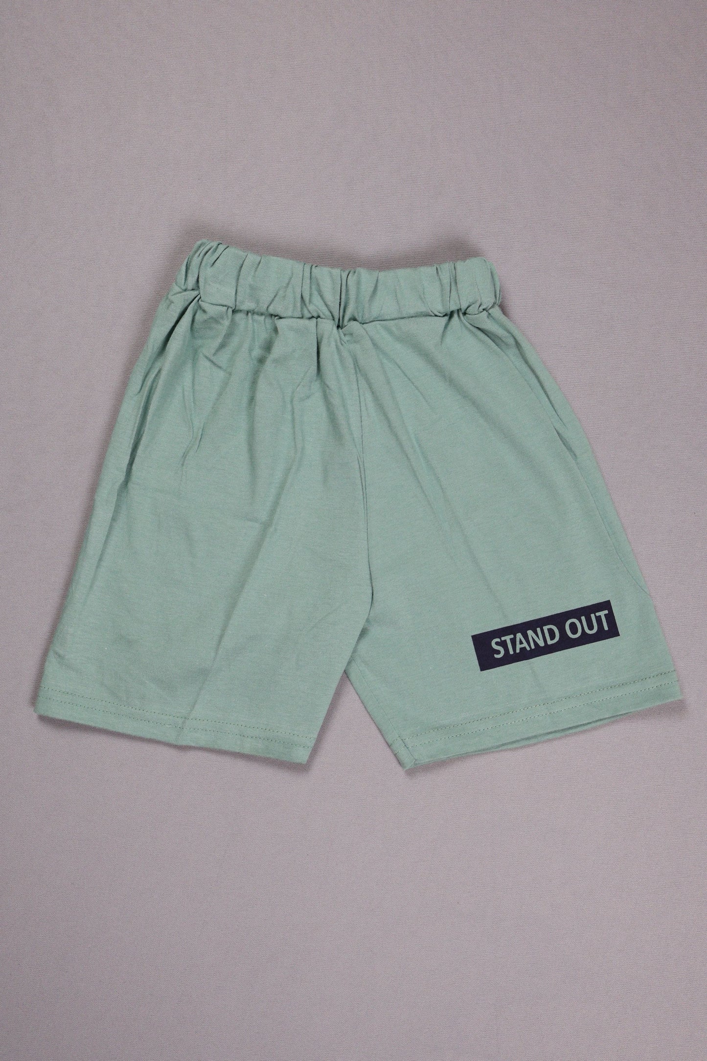 Light green shorts with a 'STAND OUT' label on a gray background