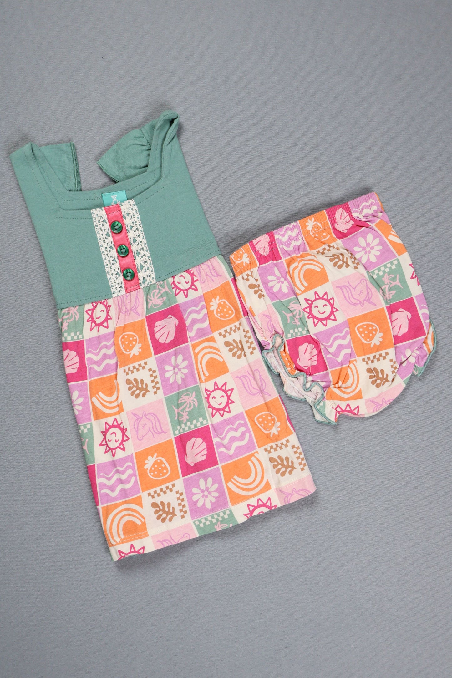 Fyst baby girl dress featuring a teal flutter-sleeve knit top with button details and a multi-color checkered skirt with sun, shell, and floral prints.