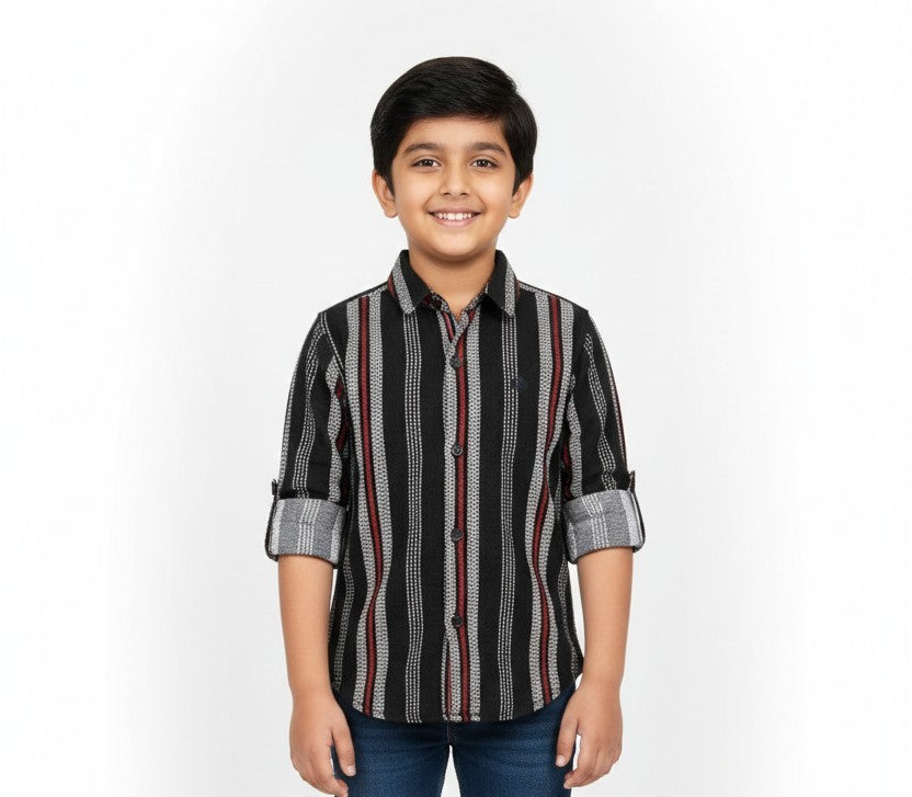 A young boy smiling in a studio portrait, modeling a Fyst brand black button-down shirt with intricate vertical patterns of grey stripes and red lines.