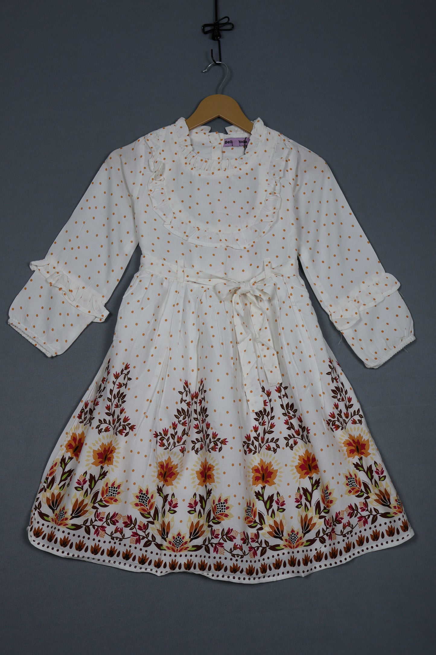 White cotton kids dress with yellow polka dots, floral print hem, and long sleeves