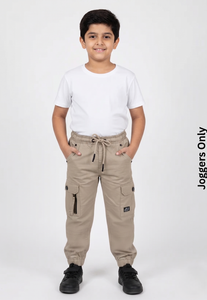 A kid modeling Fyst khaki beige cargo joggers featuring multi-functional utility pockets with button flaps, a decorative side zipper, and a comfortable drawstring elastic waistband