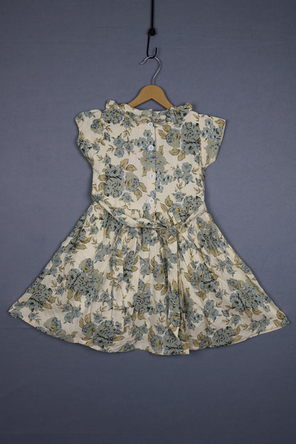Floral cotton kids dress with buttons, short sleeves, and pastel prints on a hanger