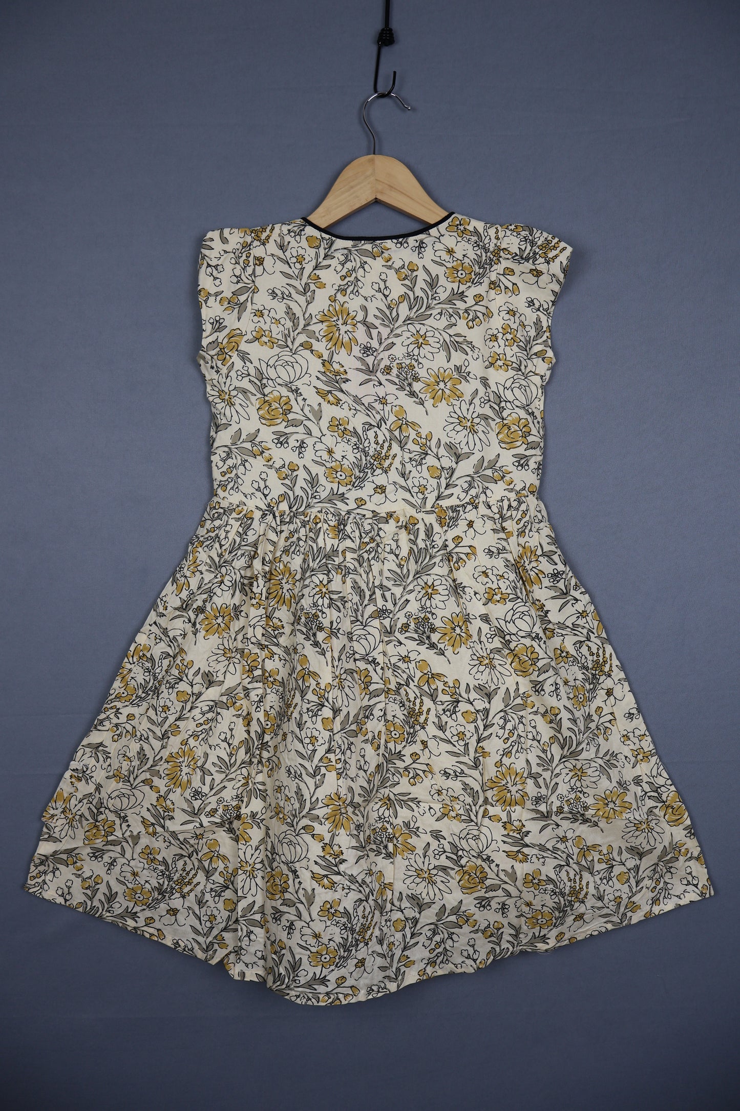 Kids cotton dress with yellow and grey floral print on a hanger against a plain background