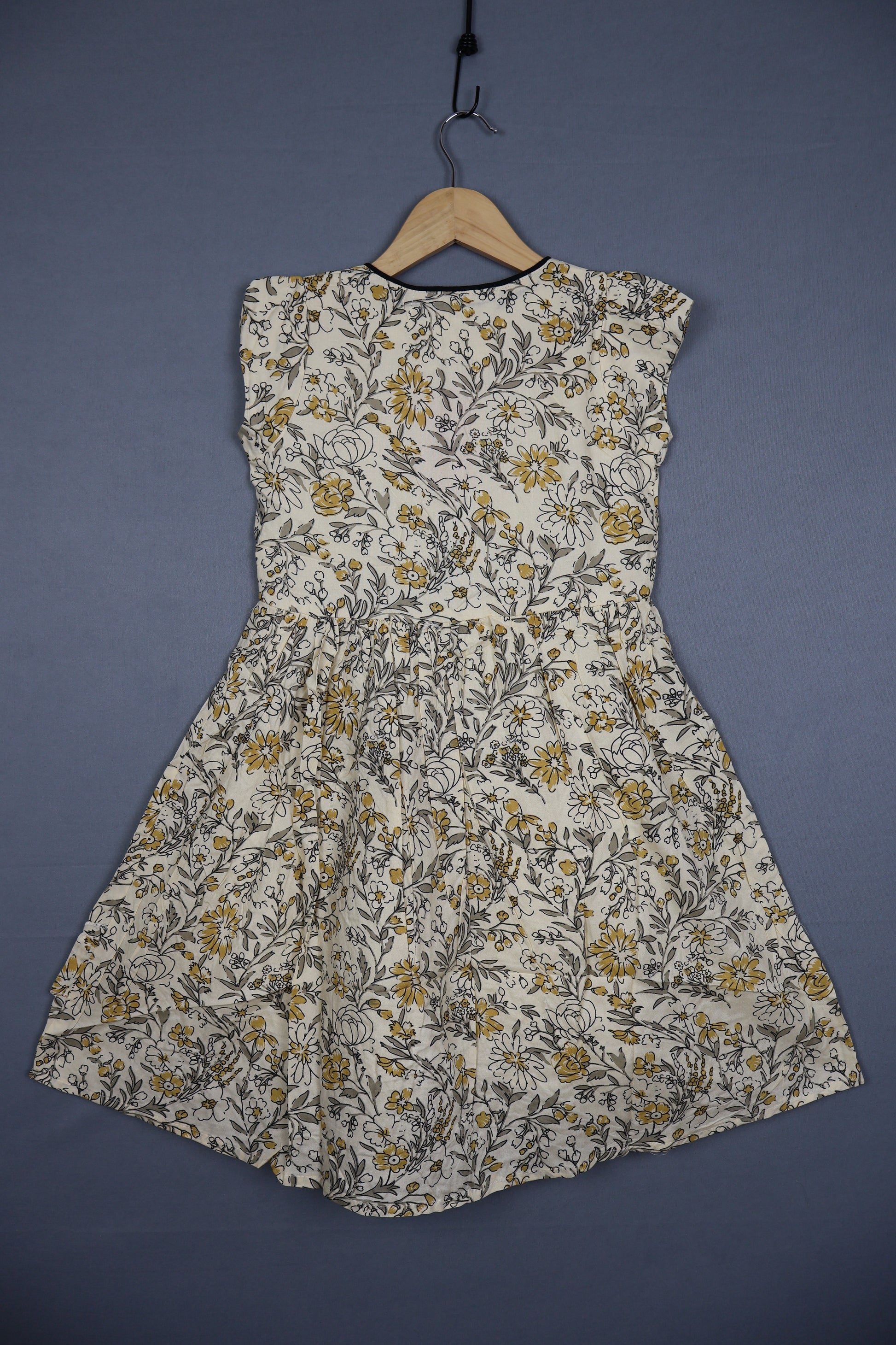 Kids cotton dress with yellow and grey floral print on a hanger against a plain background