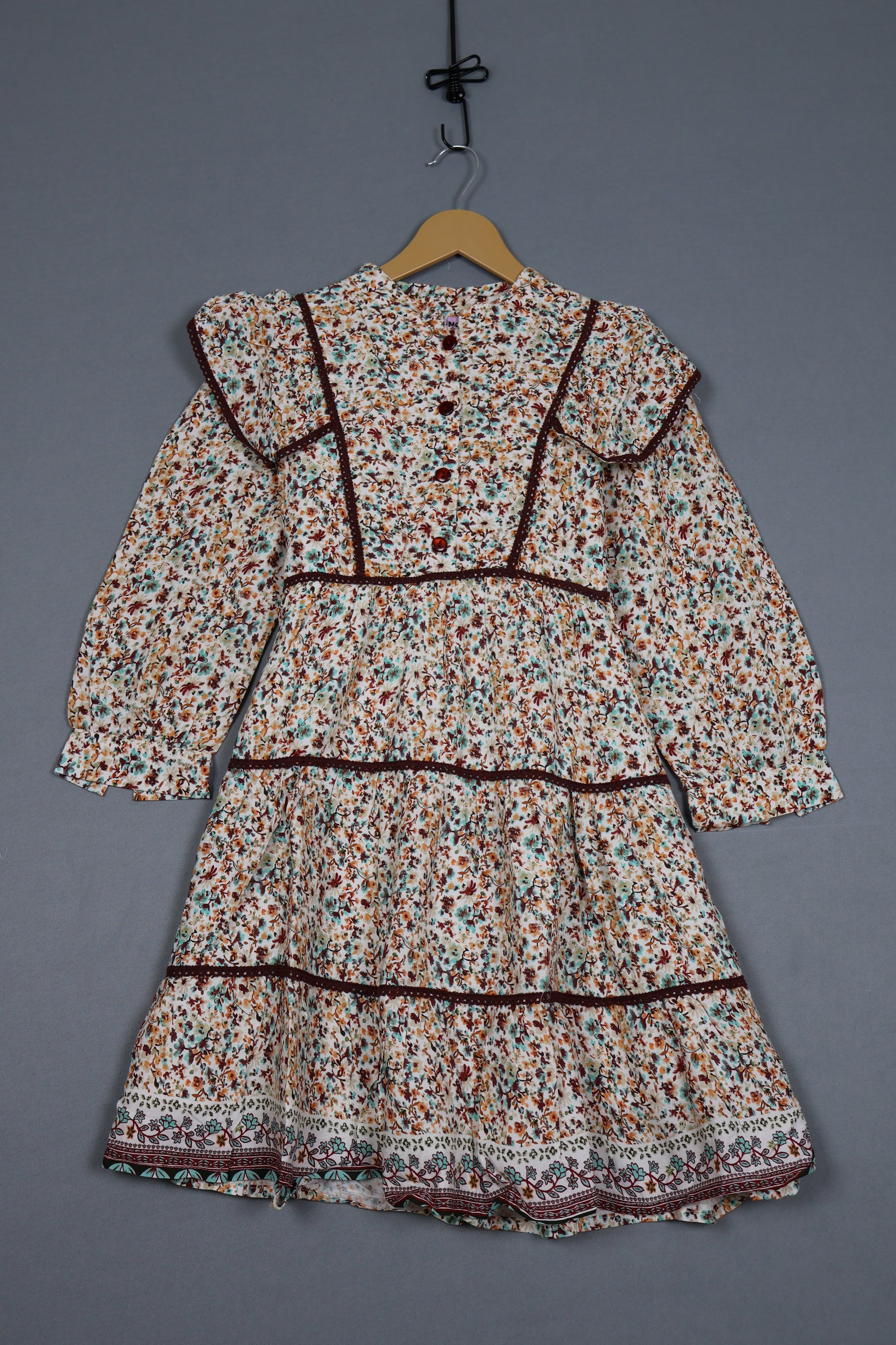Floral-patterned garment on a hanger against a gray background