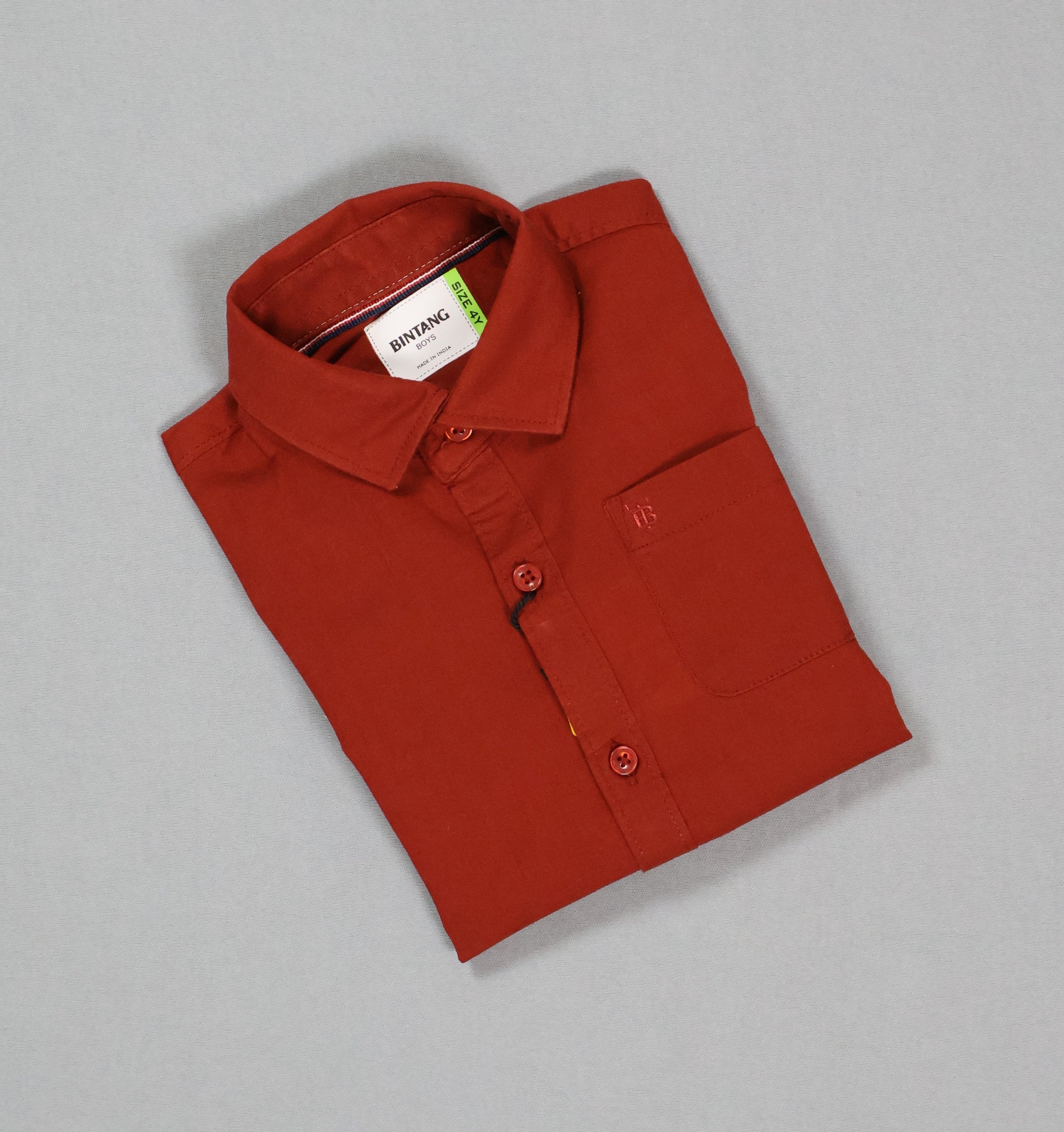 Folded red shirt with a tag on a gray background
