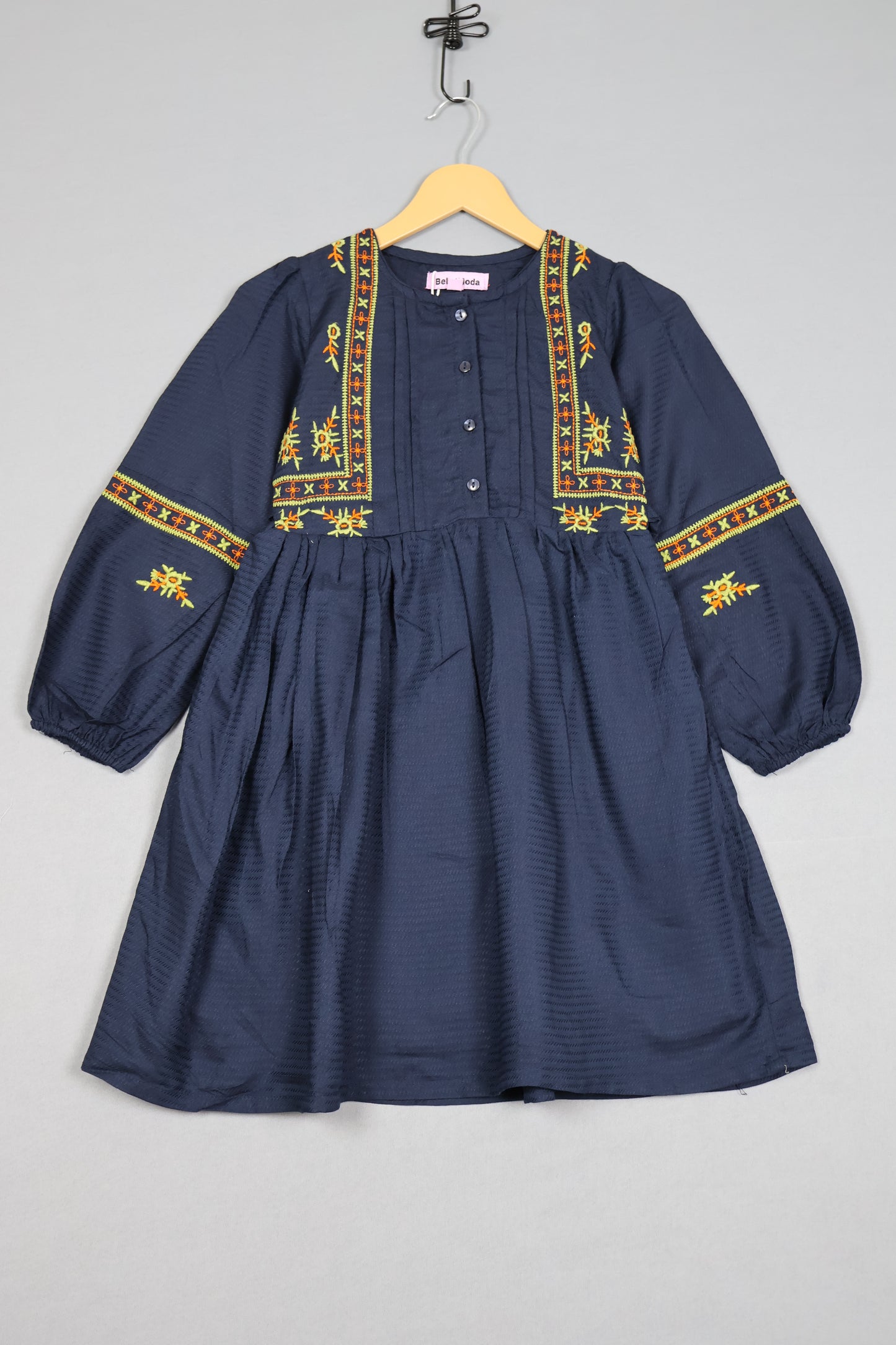 Navy blue shirt with gold embroidery on a gray background