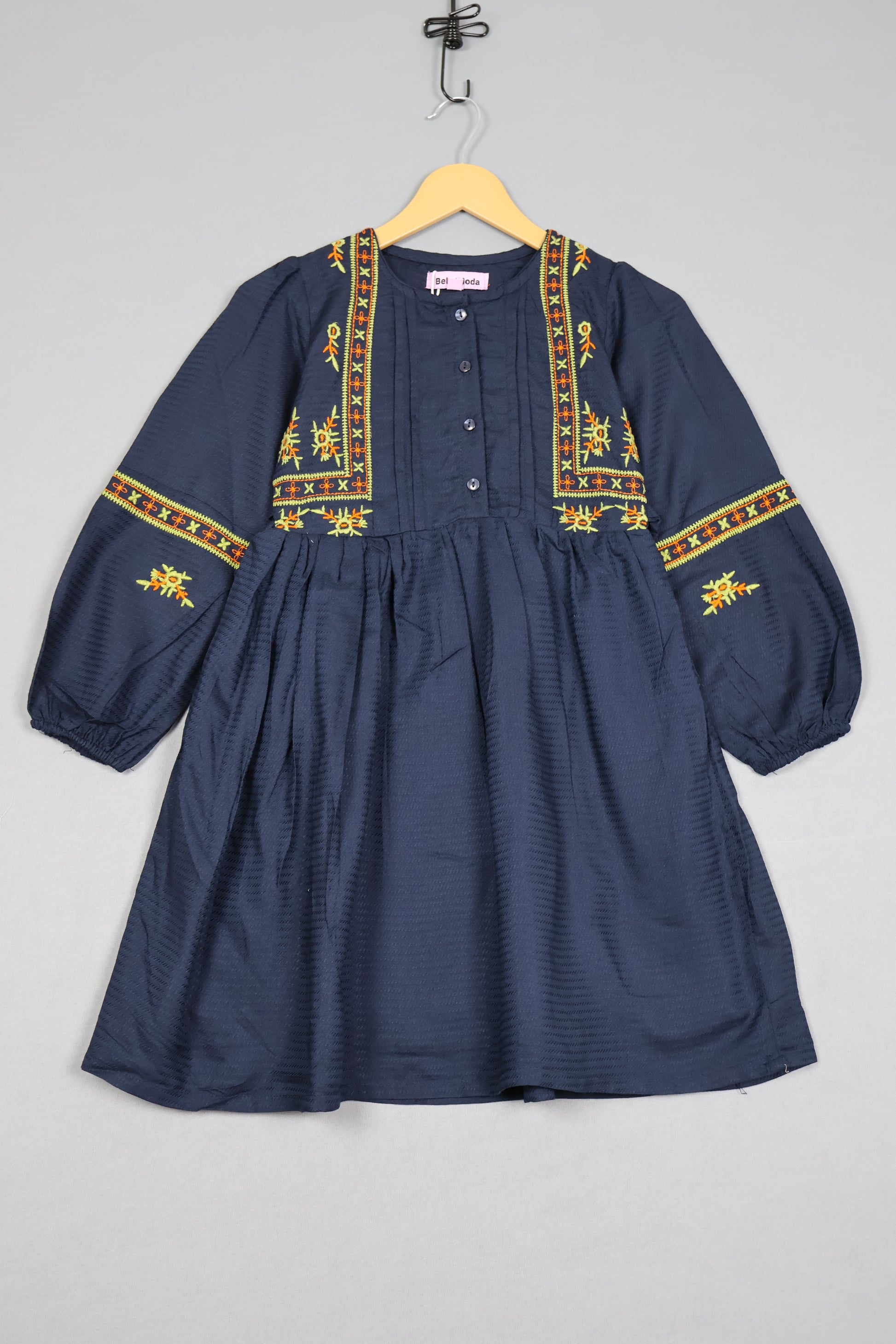 Navy blue shirt with gold embroidery on a gray background