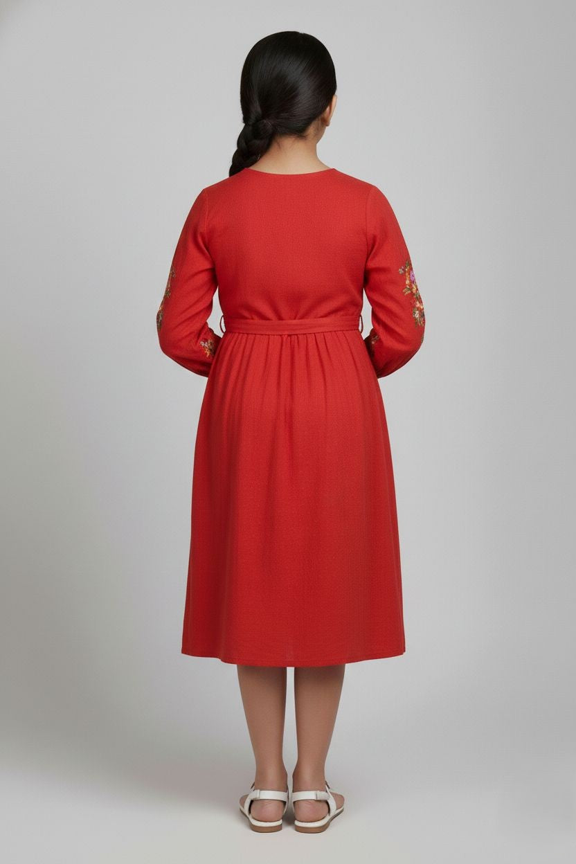 Girl in crimson red cotton frock with long sleeves and floral embroidery, back view