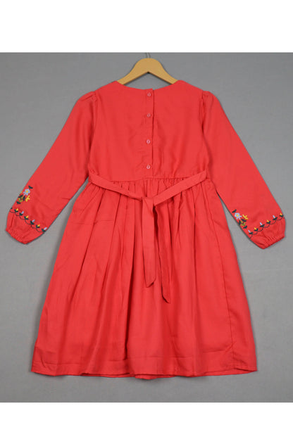 Crimson red cotton girls frock with floral embroidery on sleeves, back buttons, and waist tie.