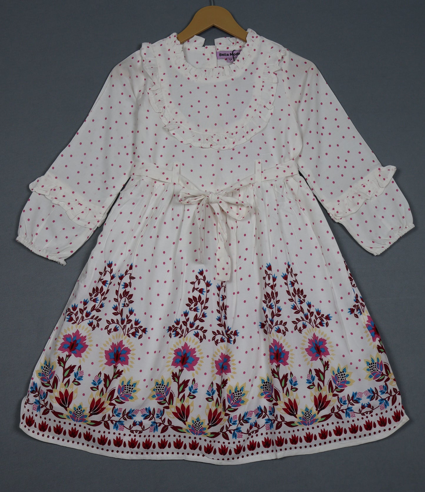 White dress with floral embroidery on a hanger against a gray background