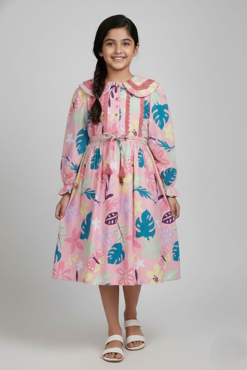 Pink long-sleeved girls' frock with a colorful floral and tropical leaf print, featuring a lace-trimmed Peter Pan collar, button-down bodice, and a drawstring waist with tassels