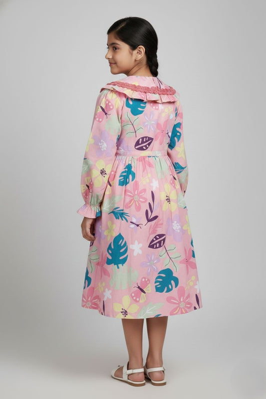 Girl wearing blush pink cotton frock with tropical floral and leaf print, back view